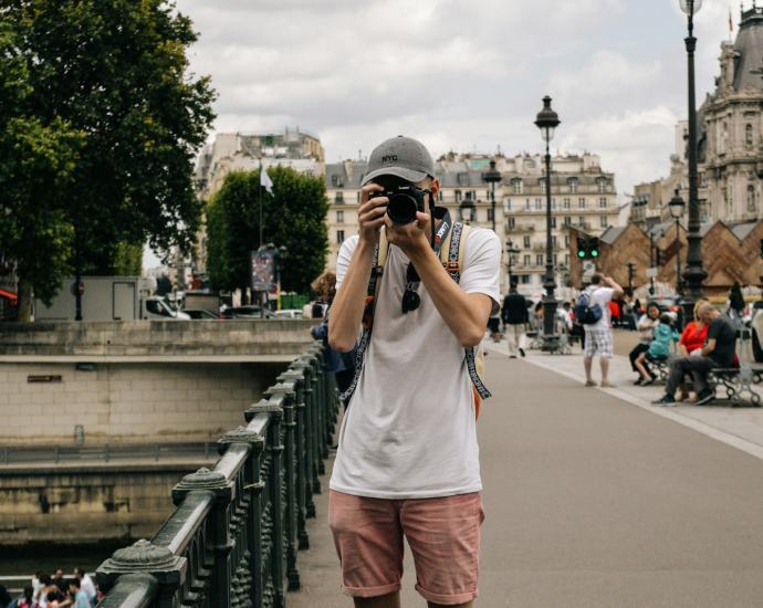 man holding DSLR camera beside bridge