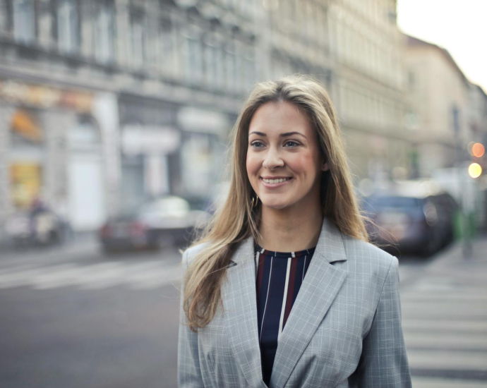Confident businesswoman smiling outdoors in urban Budapest setting.