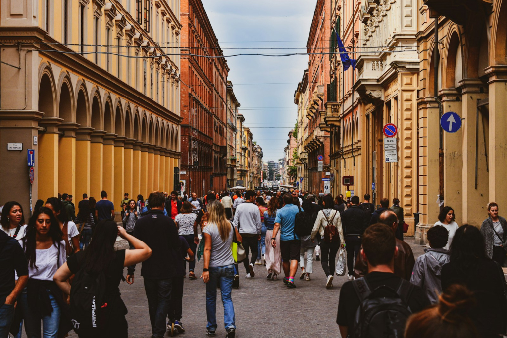 a group of people walking down a street next to tall buildings