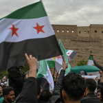 A group of people holding flags in front of a building