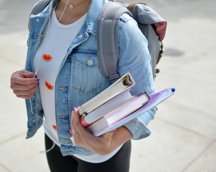 woman wearing blue denim jacket holding book