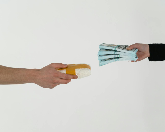 Conceptual image of a drug deal exchange showing money for a substance in two hands.