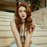 A woman with red hair sitting on a set of stairs