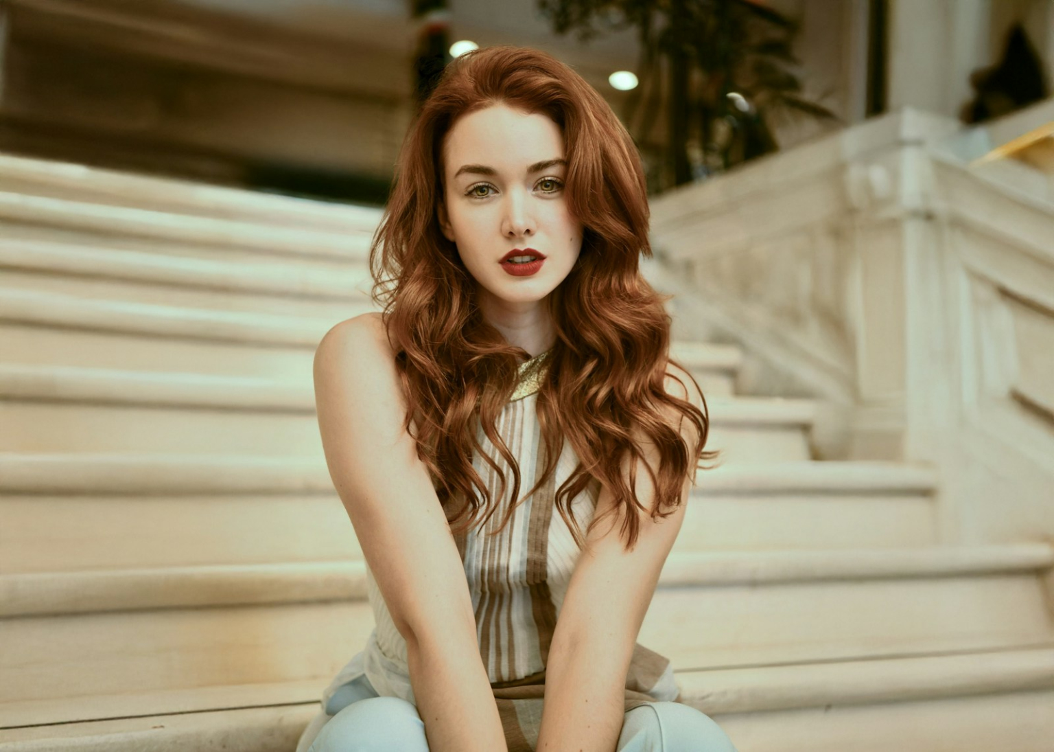 A woman with red hair sitting on a set of stairs