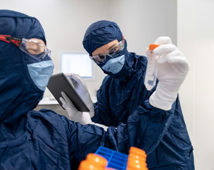 a few people in surgical scrubs and masks using a tablet