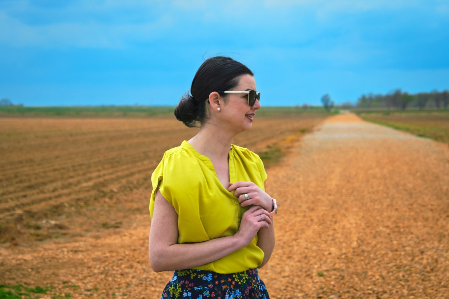 A woman poses on a rural road.