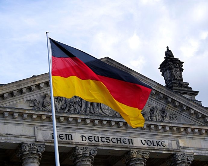 German national flag waving in front of the Reichstag building in Berlin, a symbol of democracy.