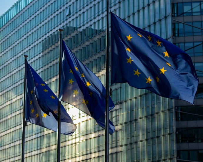 EU flags waving in front of the European Commission building in Brussels, Belgium.