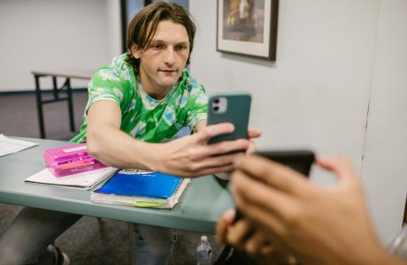 A student sharing his phone screen with another in a classroom setting.