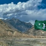 a pakistan flag flying in front of a mountain range