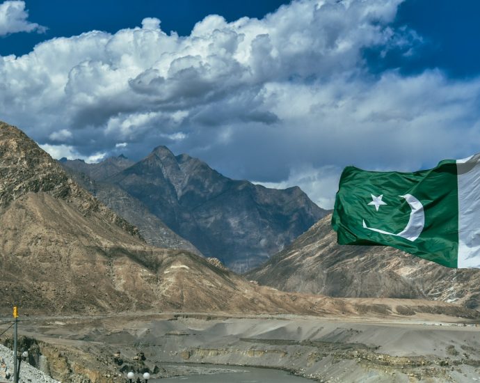 a pakistan flag flying in front of a mountain range