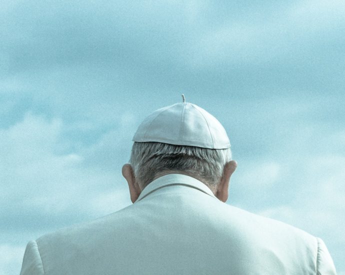 person wearing white cap looking down under cloudy sky during daytime