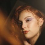 A woman with red hair looks directly into the camera.