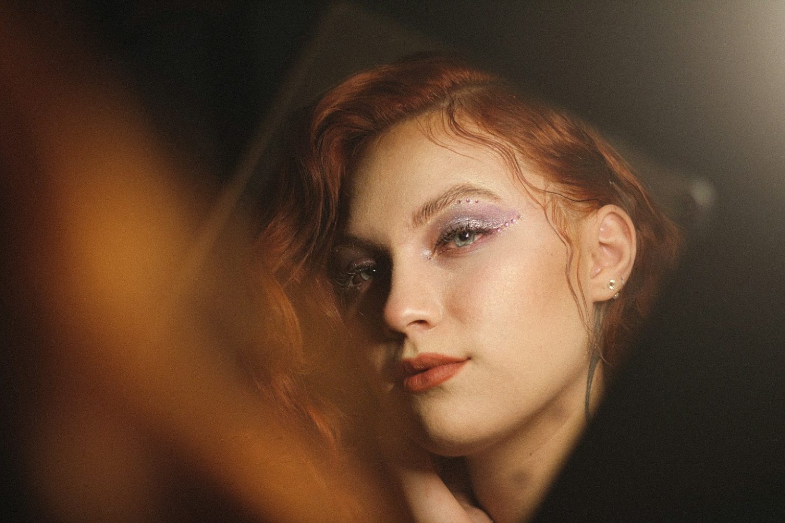 A woman with red hair looks directly into the camera.