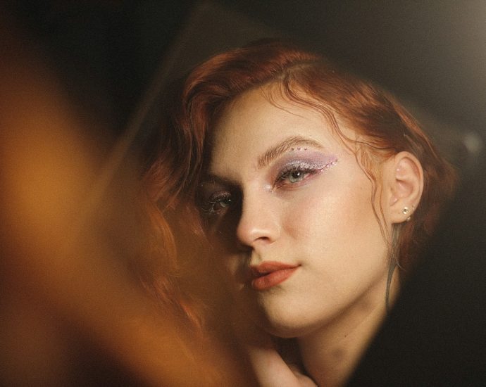 A woman with red hair looks directly into the camera.