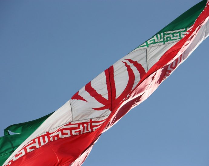 two flags flying in the wind with a blue sky in the background