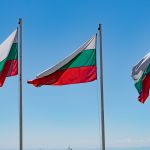 three flags flying in the wind on a sunny day