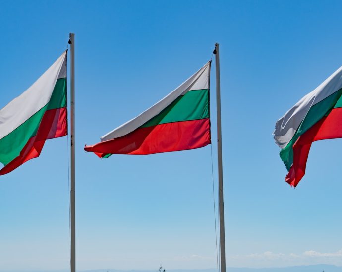 three flags flying in the wind on a sunny day