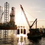 An oil rig being serviced by a supply ship.