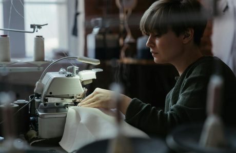 Woman using an overlock machine in a sewing workshop, showcasing concentration and craftsmanship.