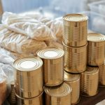 A stack of canned goods and packaged foods on a table, perfect for donation drives.
