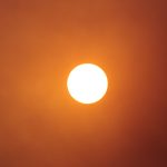 The sun shines brightly in the orange sky.