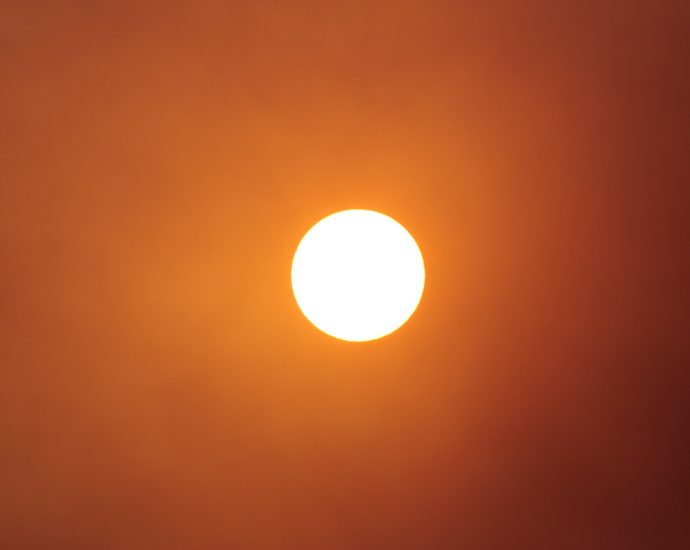 The sun shines brightly in the orange sky.