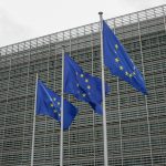 three european flags flying in front of a building