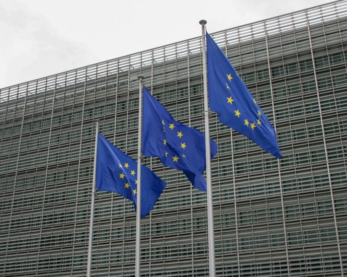 three european flags flying in front of a building