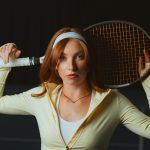 A young woman holds a tennis racket.