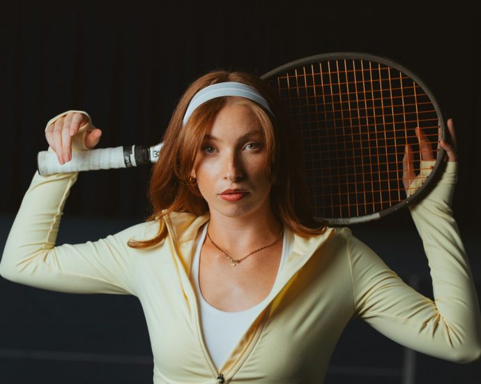 A young woman holds a tennis racket.