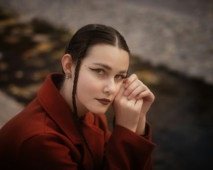 A woman poses with hands near her face.