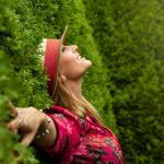 A joyful woman enjoying nature, embracing freedom in a lush green park.