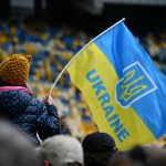A child waving the Ukrainian flag in a stadium in Kiev, showcasing patriotism and unity.