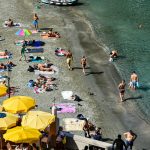 a group of people on a beach with yellow umbrellas