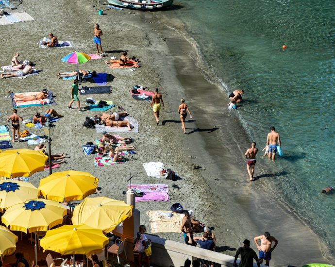 a group of people on a beach with yellow umbrellas