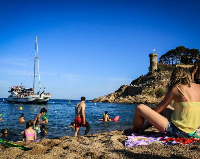 a group of people sitting on top of a sandy beach