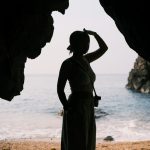 A woman silhouetted, looking out over the sea.