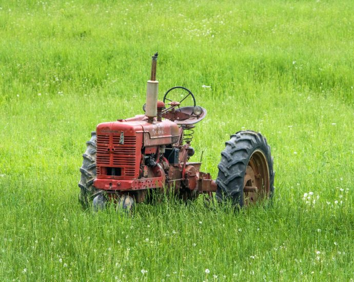 red tractor left in grass field