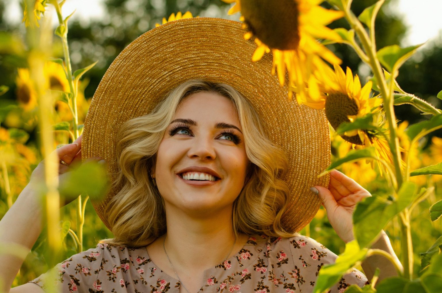 a woman in a sunflower field wearing a straw hat