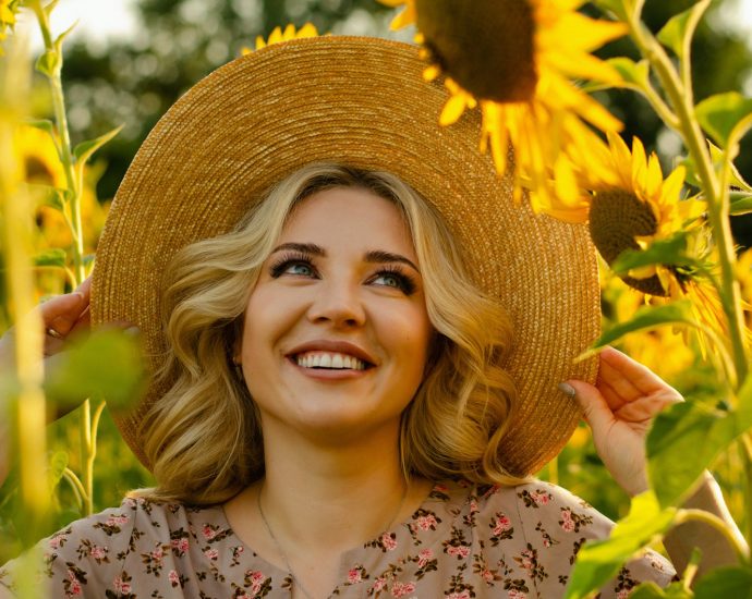 a woman in a sunflower field wearing a straw hat