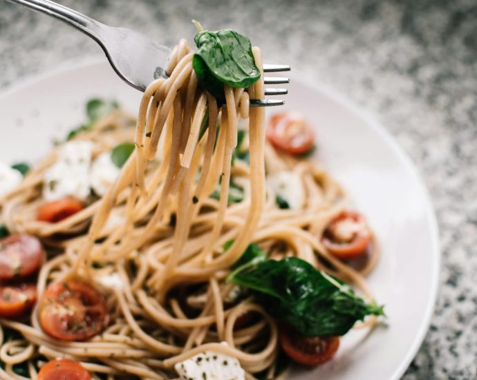 Delicious whole wheat pasta with fresh spinach, cherry tomatoes, and feta cheese in a close-up shot.