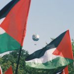 Palestinian flags with a Welt hot air balloon in Berlin, symbolizing awareness and protest.