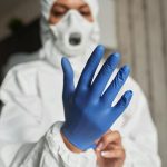 Close-up of a healthcare worker putting on blue latex gloves for protection.