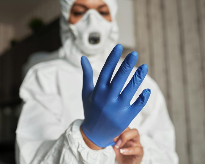 Close-up of a healthcare worker putting on blue latex gloves for protection.