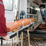 A paramedic loads a stretcher into an ambulance, showcasing emergency medical services in action.