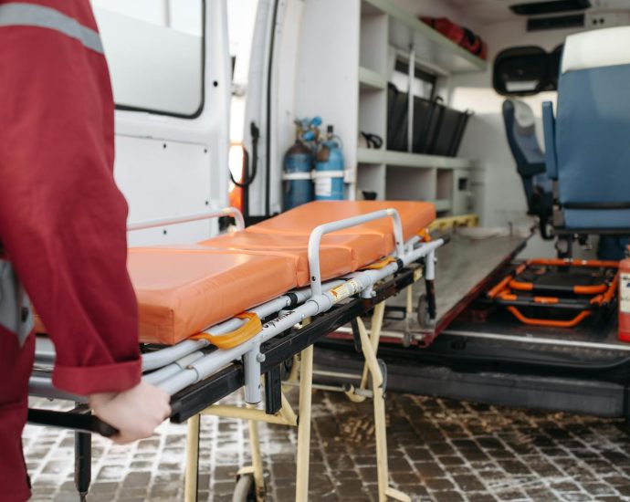 A paramedic loads a stretcher into an ambulance, showcasing emergency medical services in action.