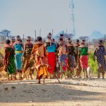 people in orange and yellow traditional dress walking on brown sand during daytime