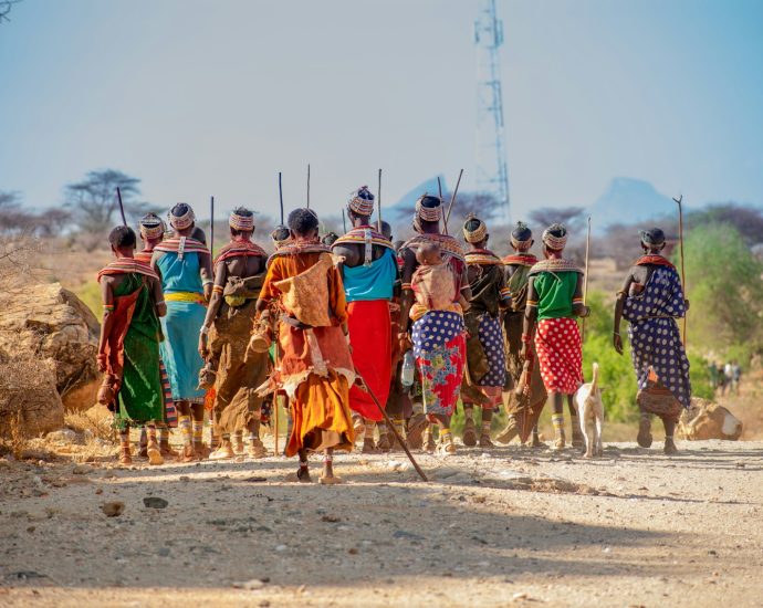 people in orange and yellow traditional dress walking on brown sand during daytime