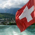 a red and white flag flying over a body of water